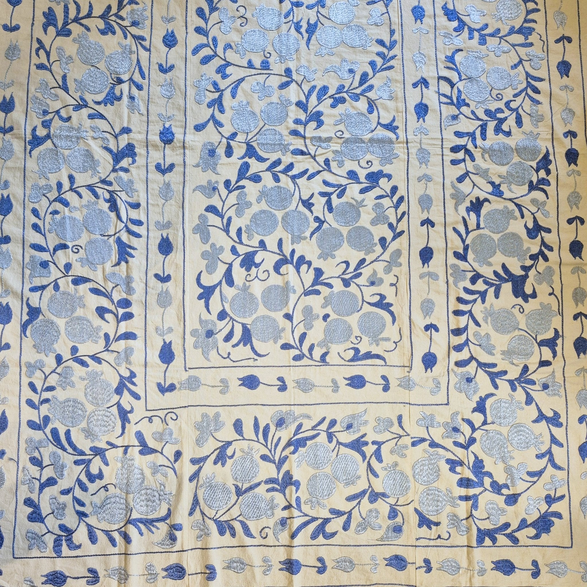 Decorative  hand embroidered suzani fabric with blue pomegranate pattern on a cream background