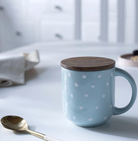 Blue polka-dot ceramic mug with a wooden lid coaster
