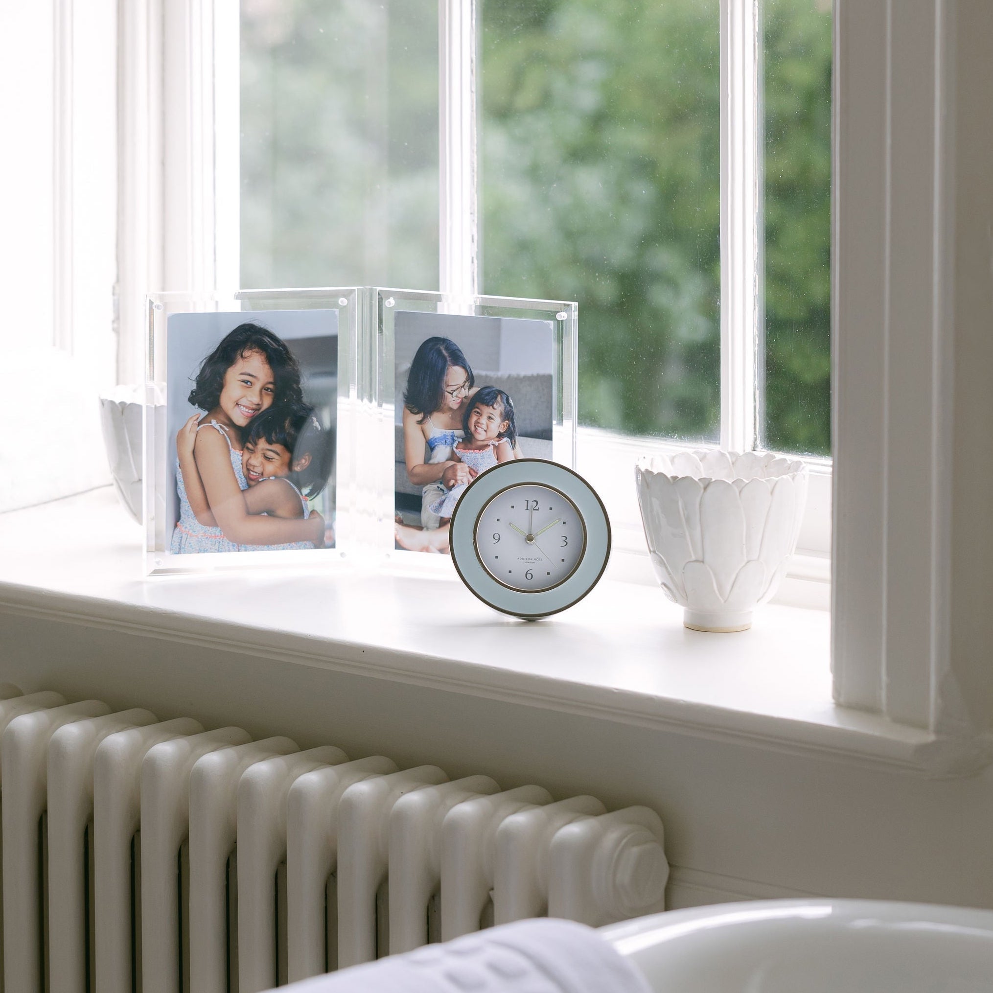 Round light blue and silver alarm clock, grey velvet backing, side view